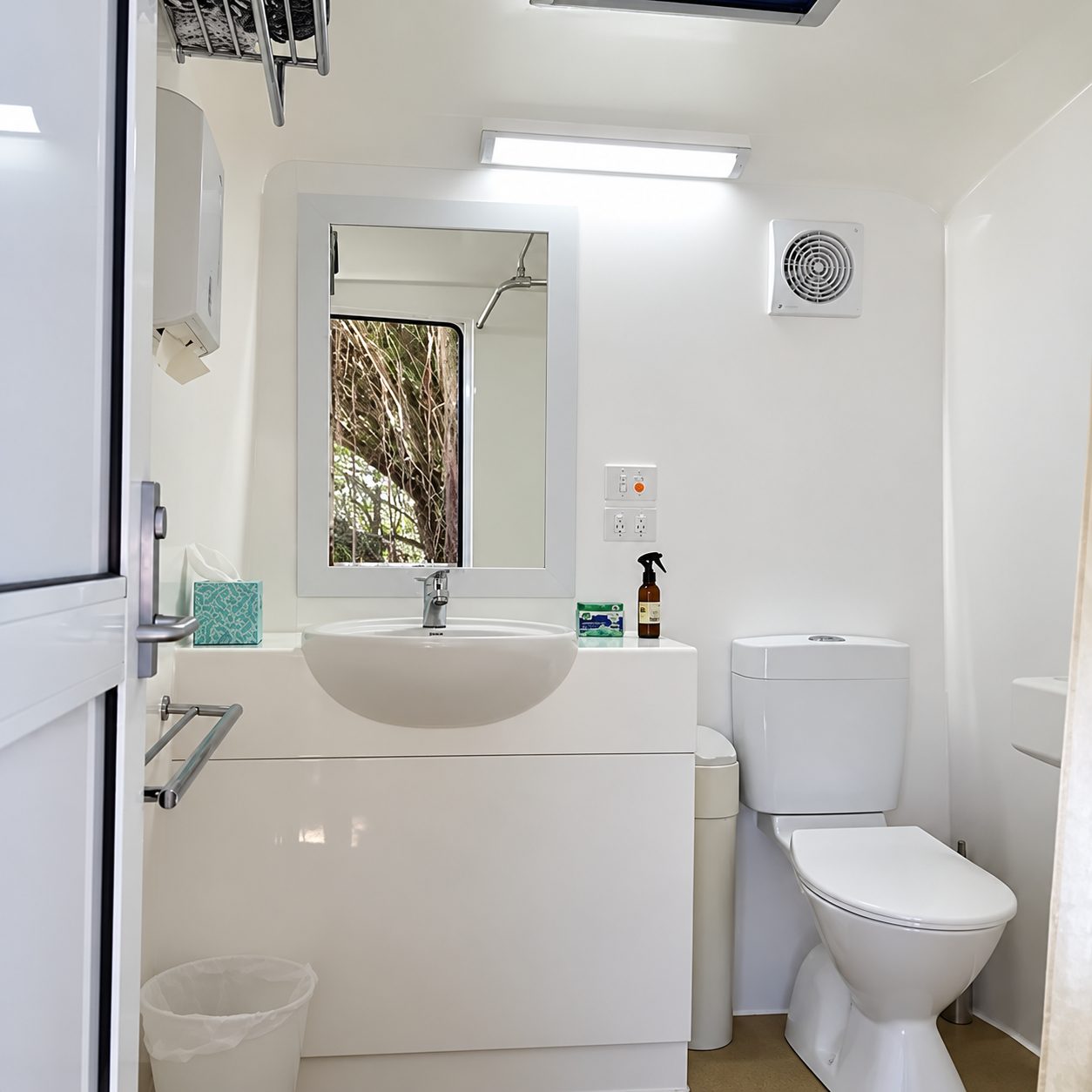 Inside the Luxury Ensuite: vanity with mirror, flushing toilet and exhaust fan