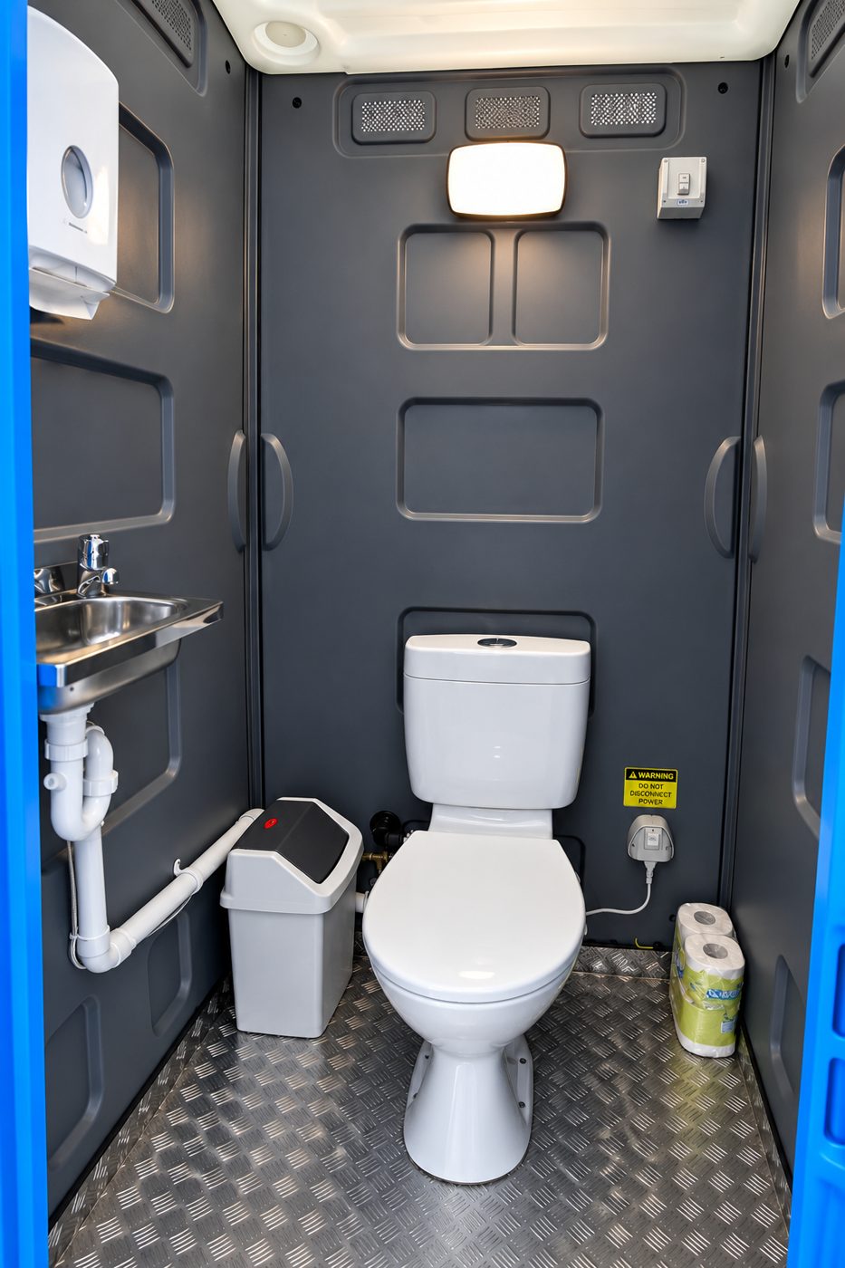 Inside: flushing toilet, stainless basin and paper towel dispenser